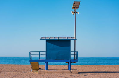 Lifeguard hut on beach against clear blue sky