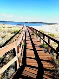 Boardwalk leading towards beach against sky