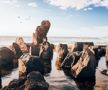 Panoramic view of rocks on beach against sky