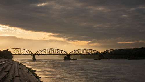 Bridge over river against sky during sunset