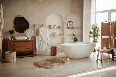 Luxury interior of big bathroom at modern african style with oval bathtub in natural lighting