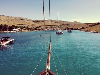 Sailboats sailing in blue river against sky on sunny day