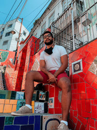 Full length of man sitting against wall