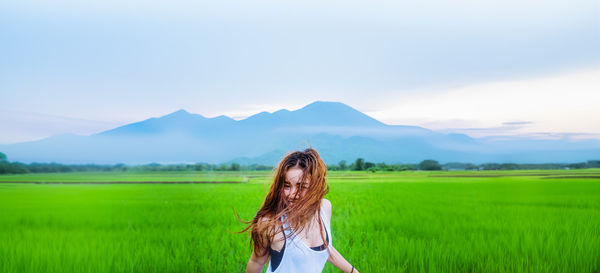 Rear view of woman standing on field against sky