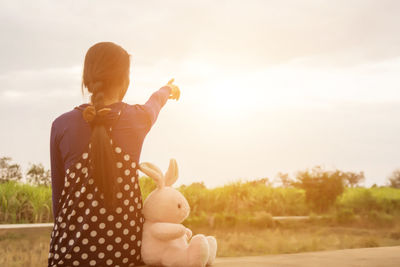 Rear view of woman with toy against sky