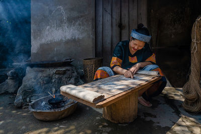 Midsection of man sitting on wood