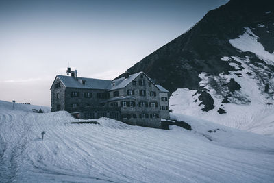 Low angle view of building on snow covered land against clear sky