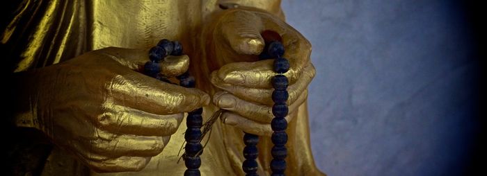 Close-up of gold giant buddha statue with beads necklace in temple