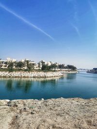 Scenic view of lake and buildings against blue sky