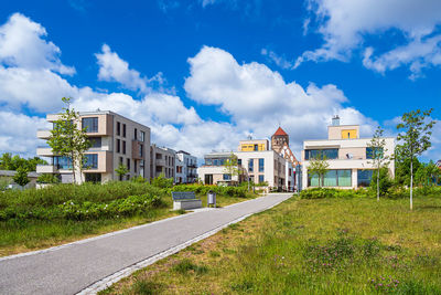 Road by buildings against blue sky