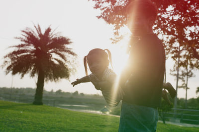 Rear view of woman standing on field against sky during sunset