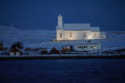 Built structure by sea against blue sky at night