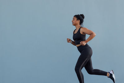 Low angle view of woman exercising against clear sky