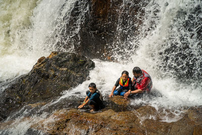 Asian family refreshing in lasir waterfall in lake kenyir, terengganu malaysia.