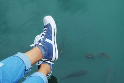Low section of woman wearing shoes over lake