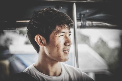 Young man with umbrella looking away while standing outdoors during rainy season