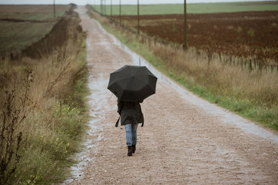 Rear view of person walking on dirt road