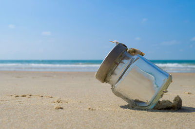 Container on beach against sky