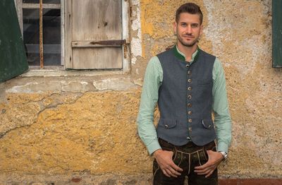 Portrait of young man standing against building in city