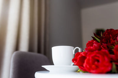 Red tulips bouquete on table, white coffee cup. concept for greeting card for mothers day