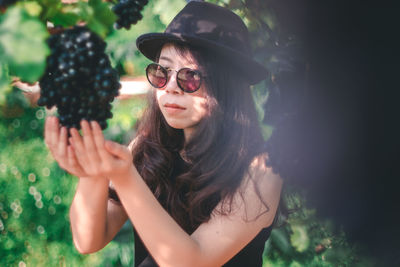 Portrait of young woman wearing sunglasses against plants