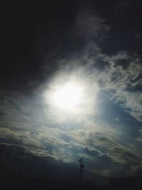 Low angle view of sun shining through clouds