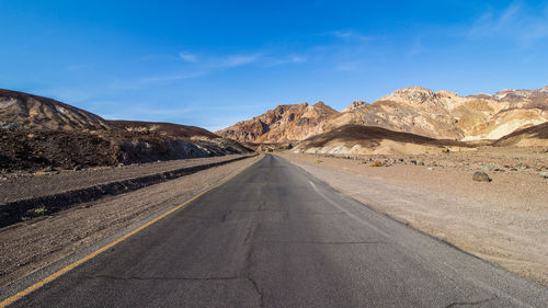 Road leading towards mountains against sky