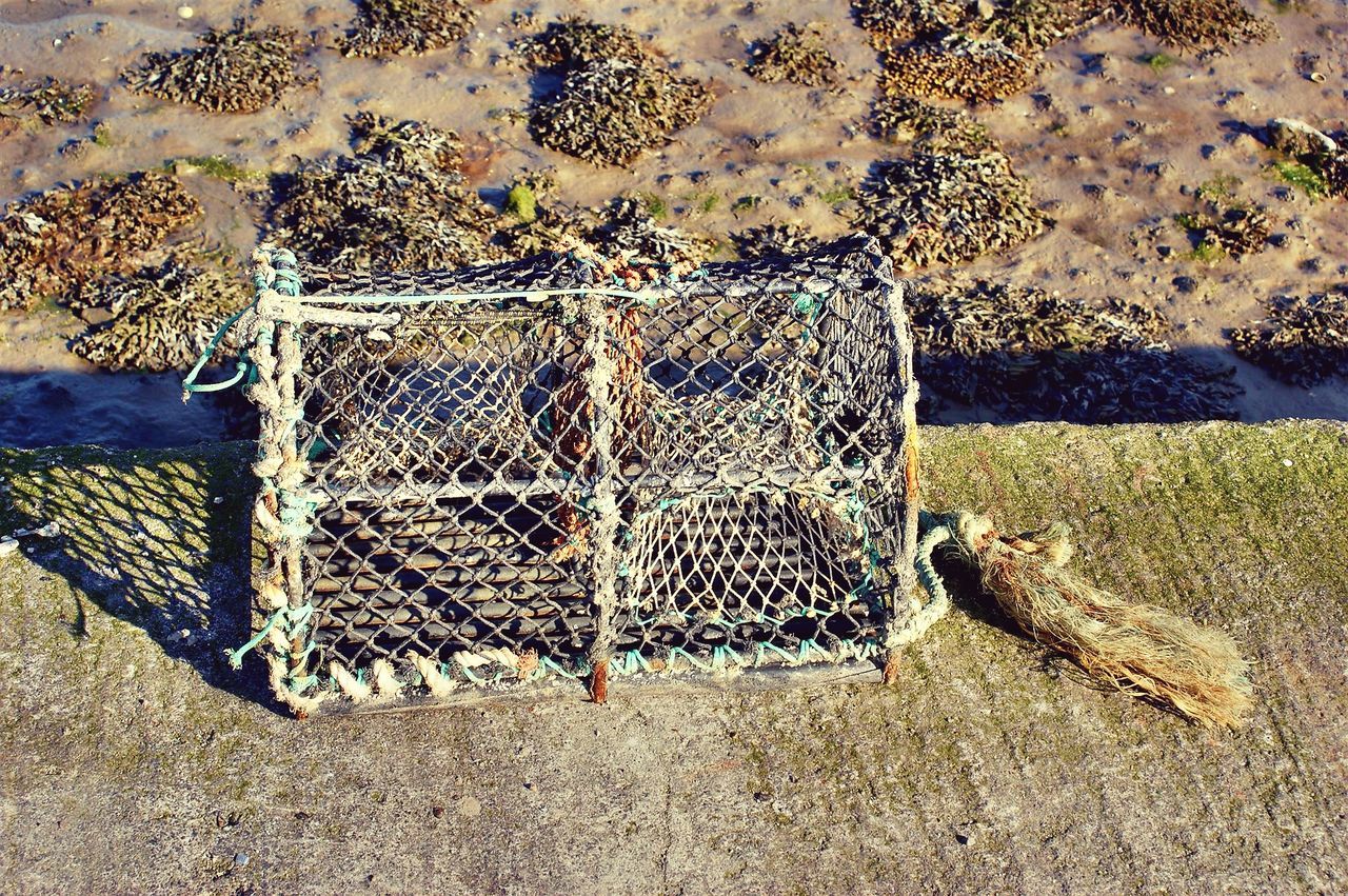 CLOSE-UP OF FISHING NET AT SHORE