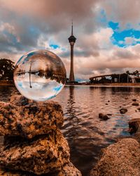Reflection of crystal ball on water in lake against sky