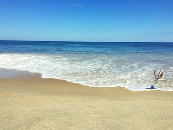 Scenic view of beach against clear blue sky