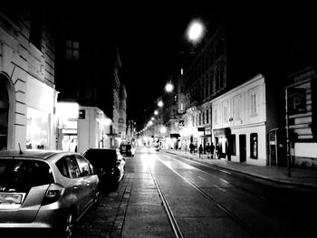 Cars on city street amidst buildings at night