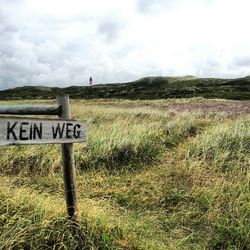 Scenic view of grassy field against cloudy sky