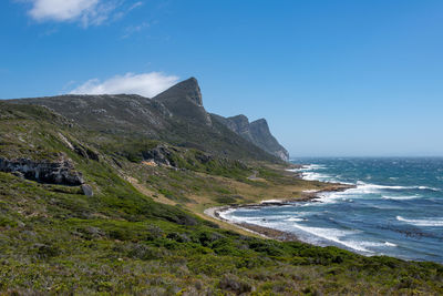 Scenic view of sea and mountains against blue sky