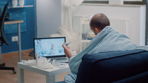 Rear view of man consulting with doctor on video call