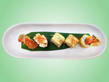 High angle view of sushi set on white plate isolated on green background