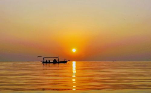 Silhouette boat in sea against sky during sunset