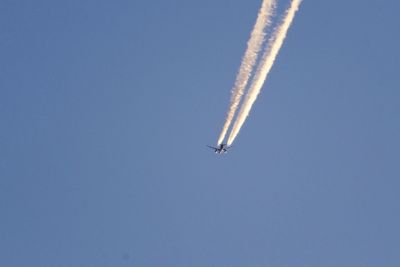 Low angle view of airplane flying against clear blue sky