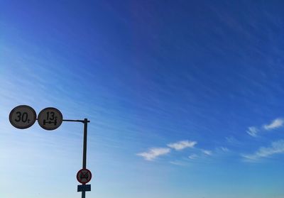 Low angle view of road sign against blue sky