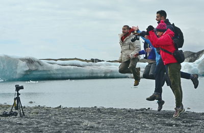 People on shore against sky during winter