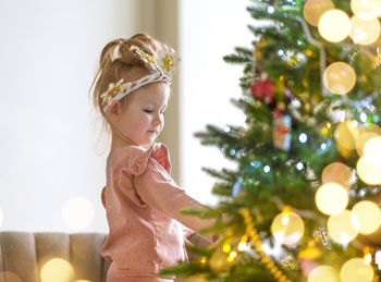 Portrait of young woman standing against christmas tree