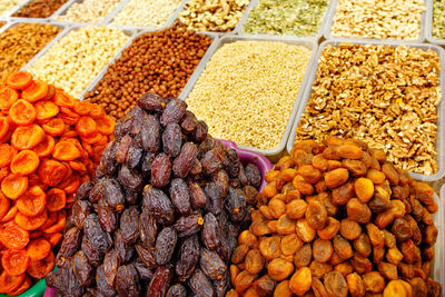 Dates, dried apricots are sold in the market on the background of various nuts, almonds, hazelnuts.