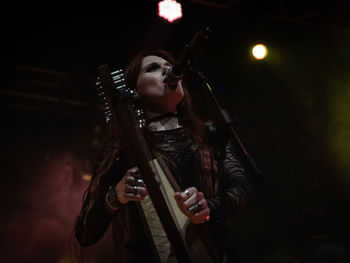 Young woman with arms raised in music concert