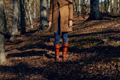 Low section of man standing on tree trunk