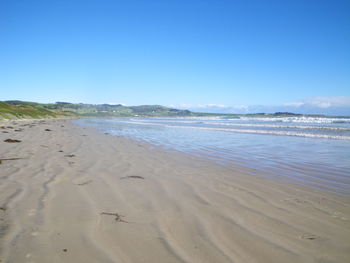 Scenic view of beach against blue sky