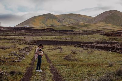 Full length of pregnant woman standing on field against sky