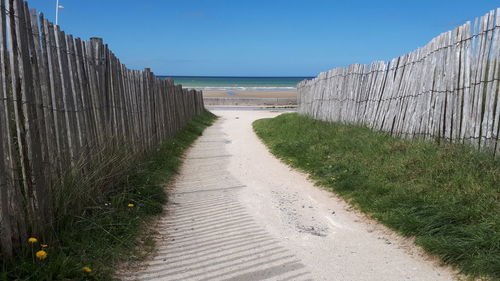 Footpath by sea against clear sky