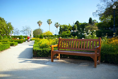 Empty wooden bench against clear sky in garden