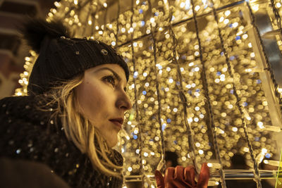 A young girl in a hat looking through christmas lights