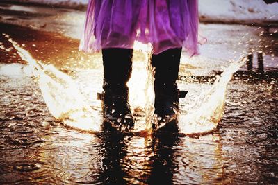 Low section of girl splashing water in puddle