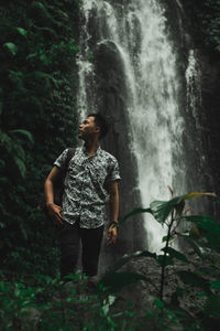 Woman standing by waterfall in forest